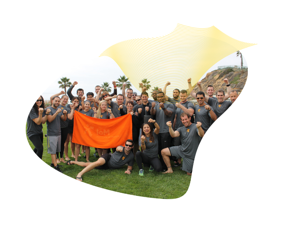 The Institute of Motion team celebrating outdoors with an IoM flag